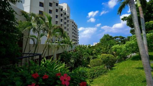a building with palm trees and flowers in a garden at The Naha Terrace in Naha