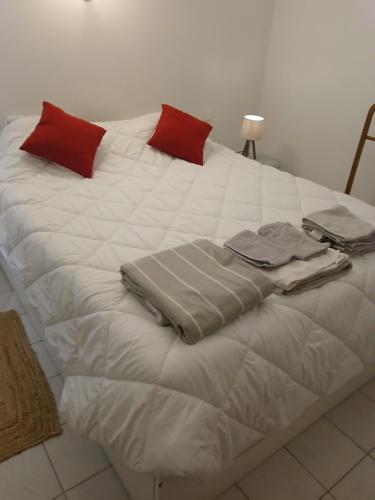 Elle comprend un grand lit blanc avec des oreillers rouges. dans l'établissement Villa des Arnoux dans la Vigne, à Draguignan