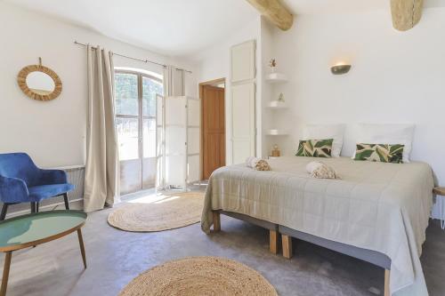 - une chambre blanche avec un lit et une chaise bleue dans l'établissement Villa Vue Luberon, à Gordes