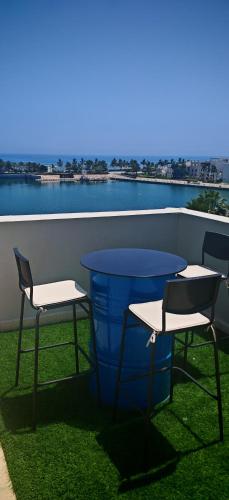 two chairs and a table on a balcony with the water at Jabal Sifah Tha Marina View Apartment in Muscat