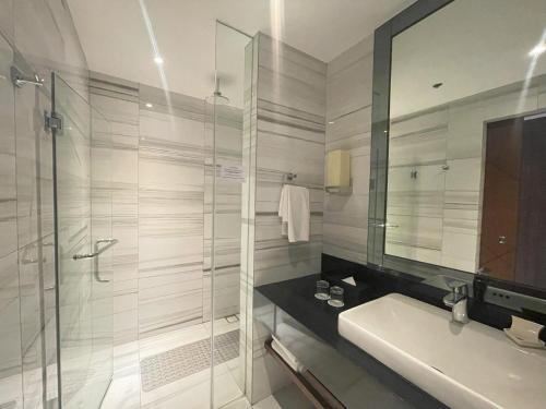 a bathroom with a shower and a sink and a mirror at Luxent Hotel in Manila