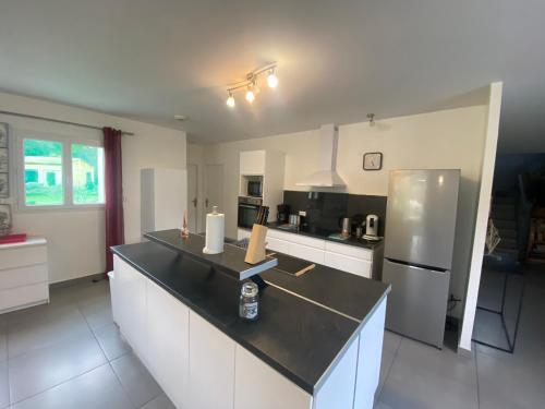 Il comprend une cuisine équipée d'un comptoir noir et d'un réfrigérateur. dans l'établissement Magnifique villa au calme a St Mitres les Remparts, à Saint-Mitre-les-Remparts