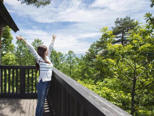 a woman standing on a balcony with her arms in the air at Izumigo AMBIENT Azumino Cottage in Azumino