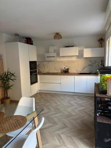 une cuisine avec des armoires blanches et une table et des chaises dans l'établissement Spacious apartment in Bandol Ideal for family or friends, à Bandol