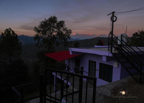 a person sitting on the roof of a house at Saanjh Binsar, Himalaya ka Dwaar in Hawālbāgh