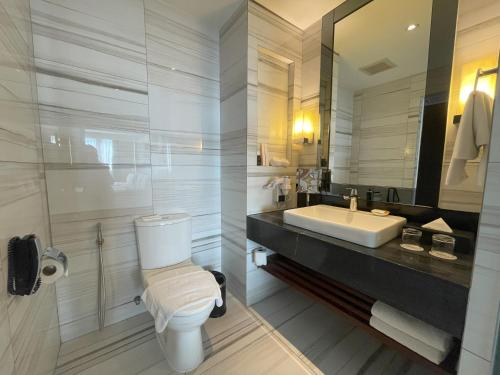 a bathroom with a white toilet and a sink at Luxent Hotel in Manila
