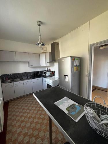 une cuisine avec une table et un réfrigérateur en acier inoxydable dans l'établissement Maison de village 4 chambres, à Neuvy-sur-Loire