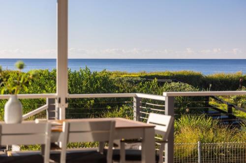 a porch with a table and chairs and the ocean at On The Sand at Mollymook Beach in Mollymook
