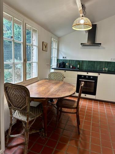 une cuisine avec une table et des chaises en bois dans l'établissement Le cottage à 40 min de Paris, à Luzarches