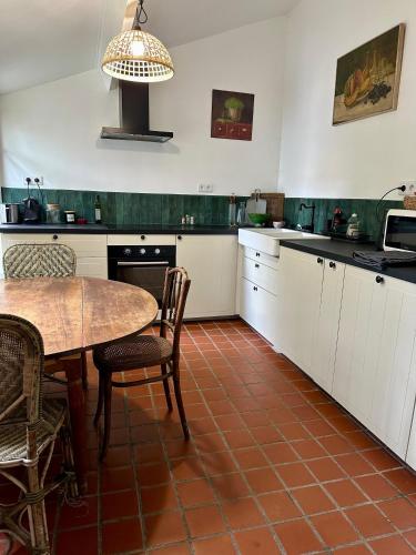 une cuisine avec des armoires blanches et une table avec des chaises dans l'établissement Le cottage à 40 min de Paris, à Luzarches