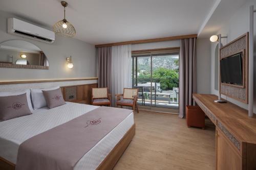 a hotel room with a large bed and a television at Monk Resort Hotel Beldibi in Kemer
