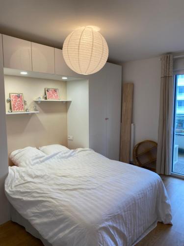 - une chambre avec un grand lit blanc et un lustre dans l'établissement Appartement à 15 min à pied du vieux port, à La Rochelle
