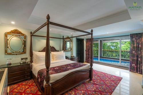 a bedroom with a canopy bed and a large window at Mayfair Spring Valley Resort Guwahati in Guwahati