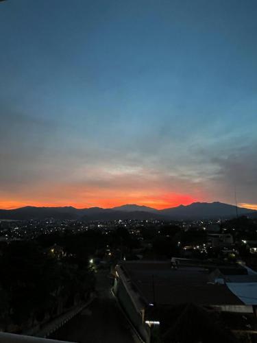 a sunset over a city with mountains in the background at Bukit Mega Raya in Geruntang