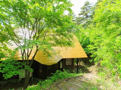 a house with a yellow roof in the woods at Izumigo AMBIENT Azumino Cottage in Azumino