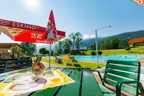 a table with an umbrella next to a swimming pool at Vitalhof am Kreischberg by ALPS RESORTS in Bodendorf