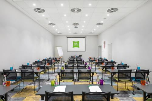 a room filled with tables and chairs with a white wall at Ibis Styles Budapest Center in Budapest