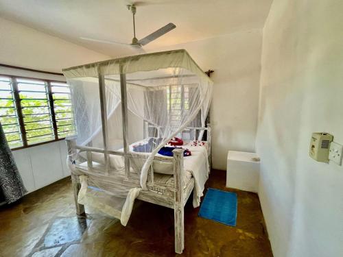 a bedroom with a canopy bed and a chair at Madenge house casa zucchero in Watamu