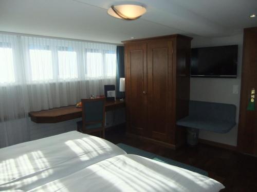a bedroom with a bed and a desk and a television at Hotel Hecht Appenzell in Appenzell