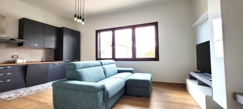 a living room with a blue chair and a kitchen at Casa Nue - Appartamento Deluxe in Posada