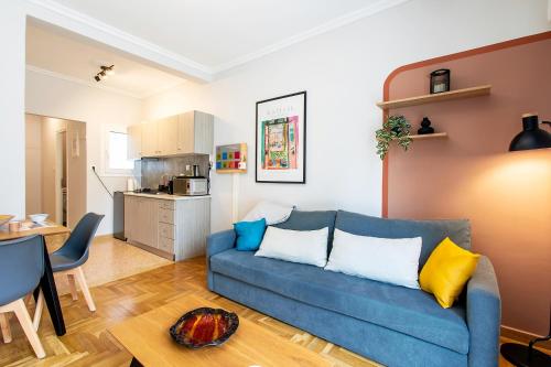 a living room with a blue couch and a kitchen at Aris123 by Smart Cozy Suites - Apartments in the heart of Athens - 5 minutes from metro - Available 24hr in Athens