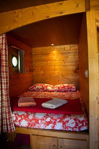 Cette chambre comprend un lit dans une cabane en rondins. dans l'établissement La Dorépontaise ROULOTTE, à Pondaurat