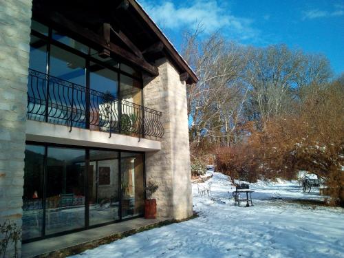 a building with glass windows and a balcony in the snow at Les Favouilles, le gîte pour 15 personnes in Dauphin