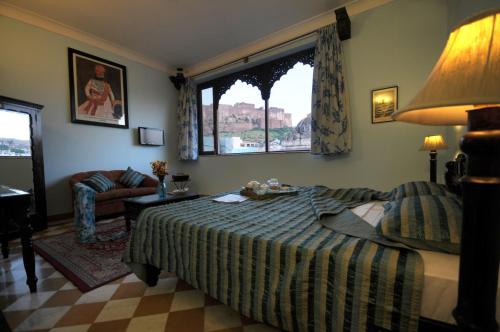 een slaapkamer met een bed, een bank en een raam bij Haveli Inn Pal in Jodhpur