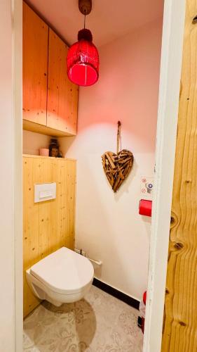 La salle de bains est pourvue de toilettes blanches et d'une lumière rouge. dans l'établissement Chic and Cozy 3-Star Apartment - 1km from Center, à Morzine