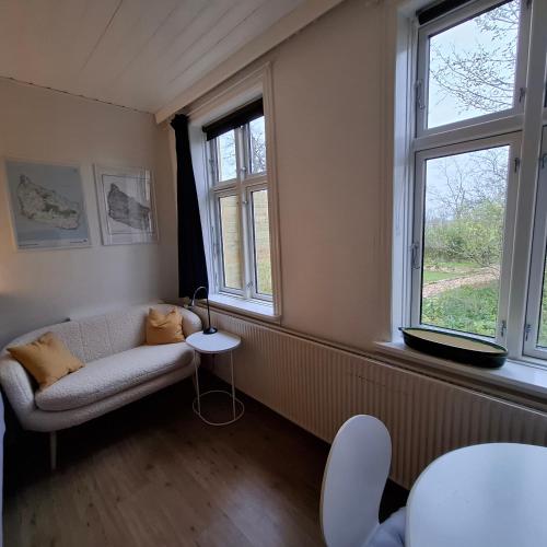 a living room with a couch and two windows at The Cherry Apartment - 'Den Gule Svane' Guest House near Rønne & Beach in Rønne