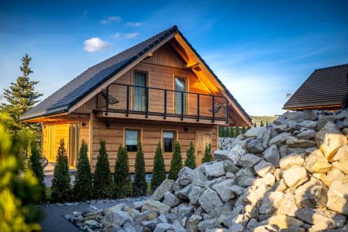 a log home with a rock wall in front of it at Świerkowa Osada in Istebna