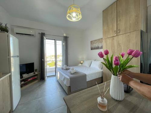 a bedroom with a bed and a vase of pink flowers at Roomie Studio Near PAGNI in Goúrnes