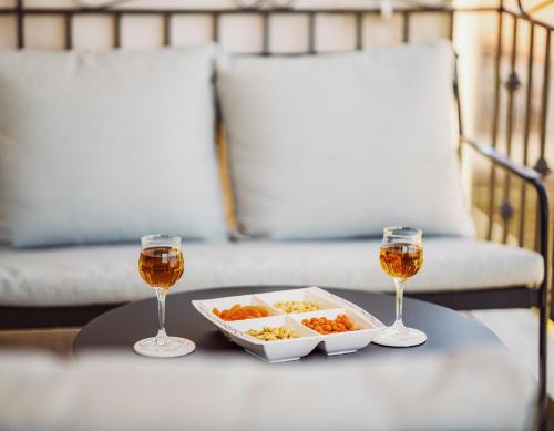 a table with a plate of food and two glasses of wine at K&E Guesthouse in Preveza