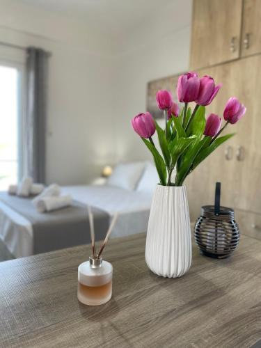 a white vase with purple flowers on a table at Roomie Studio Near PAGNI in Goúrnes