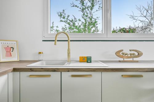 une cuisine blanche avec un évier et une fenêtre dans l'établissement La Familia - 5 pers - Jardin - Wifi, à Évreux