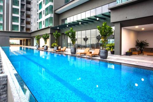 a large swimming pool in a building with chairs at SKS Pavillion Residences Johor Bahru in Johor Bahru