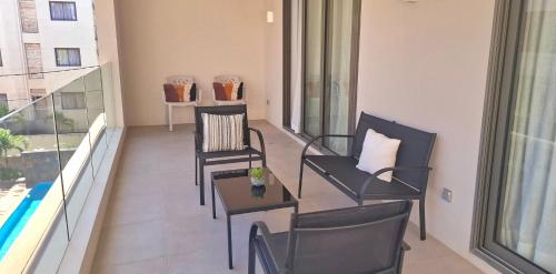 Soleia 2 - Pereybere - Appartement Cozy avec piscine proche plage في غراند بايَ: شرفة مع كراسي وطاولات على مبنى