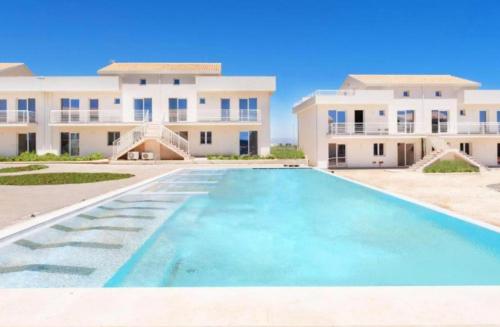 a large swimming pool in front of a building at Le Voyage Holiday Home Marzamemi in Marzamemi