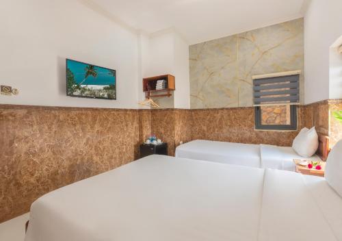 a bedroom with two beds and a tv on the wall at Khách sạn gần biển Viva Tuy Hoà Phú Yên in Phường Sáu