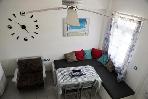 a living room with a couch and a clock on the wall at Aura Loutra Kythnos in Kithnos