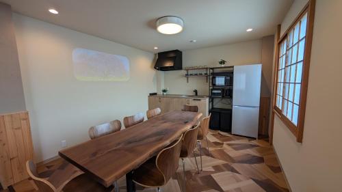 a dining room with a wooden table and a kitchen at Dream Stays TSUKI in Osaka