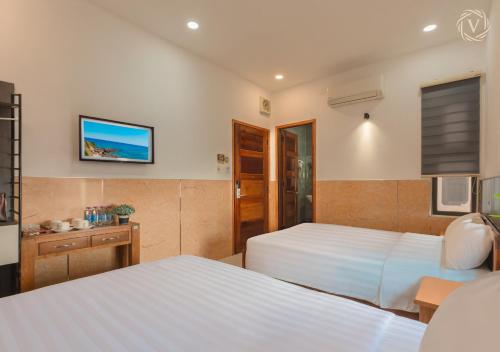 a bedroom with two beds and a tv on the wall at Khách sạn gần biển Viva Tuy Hoà Phú Yên in Phường Sáu