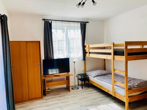 a bedroom with a bunk bed and a desk with a television at Apartmány na Horce in Blata