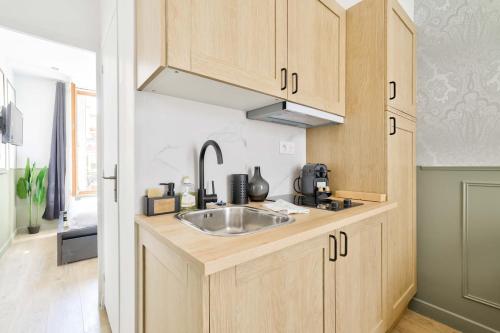 une cuisine avec des armoires en bois et un évier dans l'établissement GuestReady - Charm and Comfort near Paris, à Bagneux