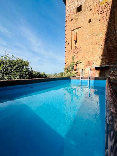 a swimming pool in front of a brick building at Truffle N Bed in San Giovanni dʼAsso