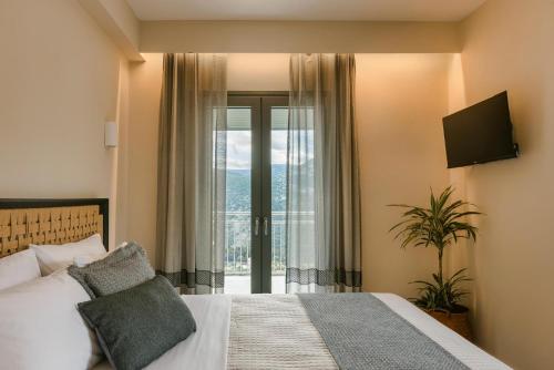 a bedroom with a bed and a large window at Anax by Vintage Travel in Ayia Evfimia
