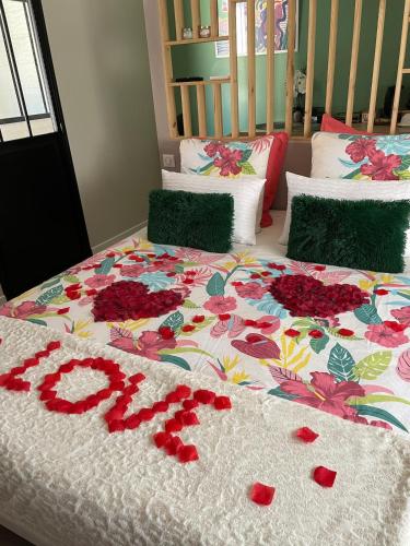 - un lit avec une couverture de fleurs avec le mot amour dans l'établissement Suite romantique Au cœur du Spa avec jacuzzi et sauna privatif proche de Toulouse, à Auterive