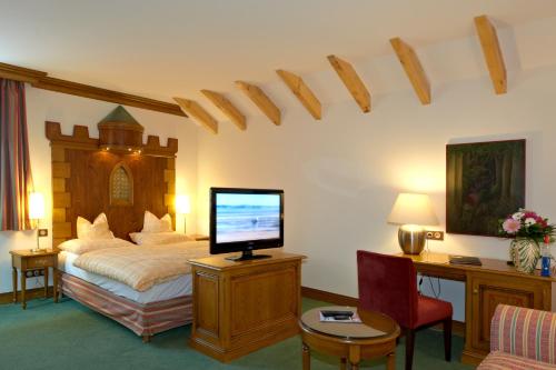 a bedroom with a bed with a television and a desk at Chez Jean in Saverne