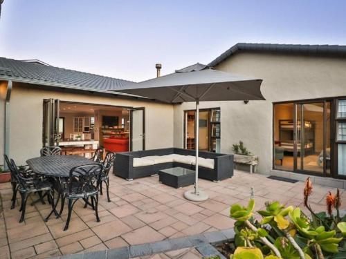 a patio with a table and chairs and an umbrella at Kamma Kai Beach Villa in Sedgefield