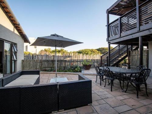 a patio with a table and an umbrella at Kamma Kai Beach Villa in Sedgefield